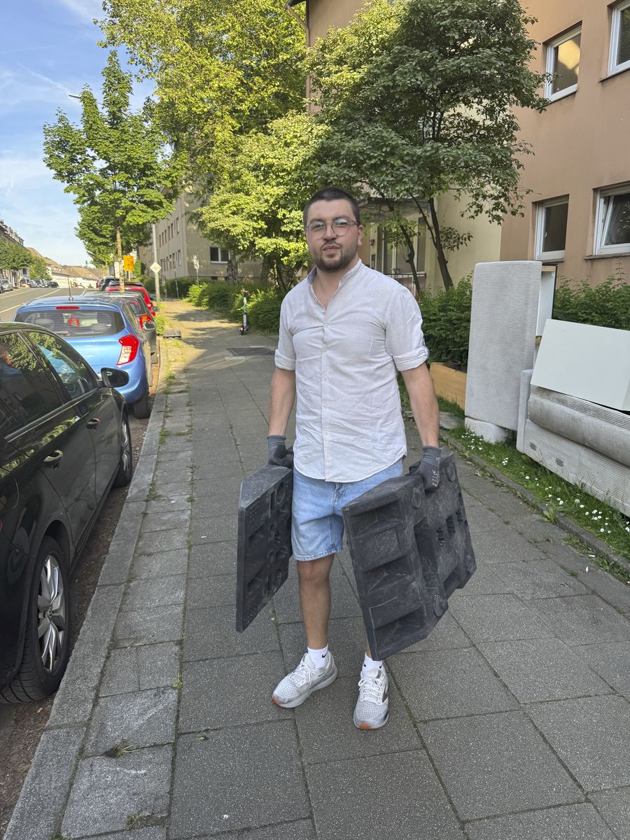 Inhaber von ZoneService trägt Betonfüße auf dem Gehweg entlang parkender Autos