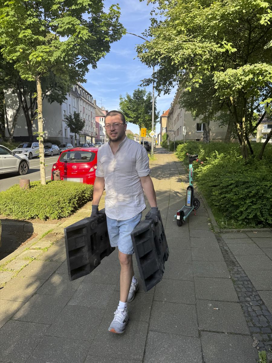 Inhaber trägt zwei Betonfüße für die Halteverbotszone über den Gehweg