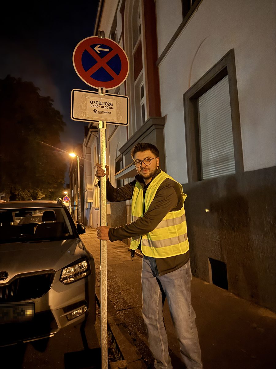 Baris Coskun, Inhaber von ZoneService, stellt in Warnweste nachts ein Halteverbotsschild in Mülheim an der Ruhr auf