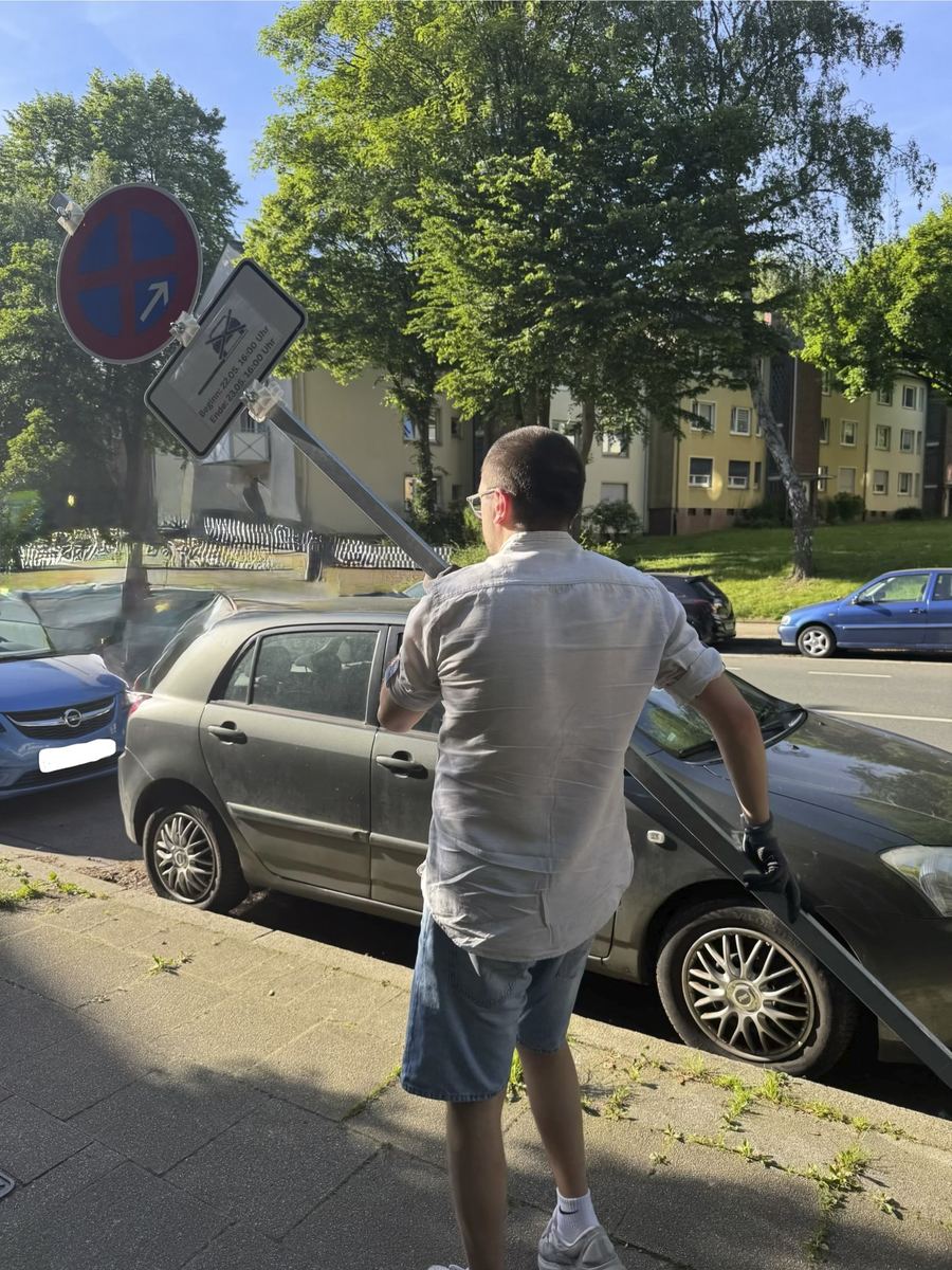 Aufrichten der Schilderstange am Straßenrand zwischen parkenden Autos
