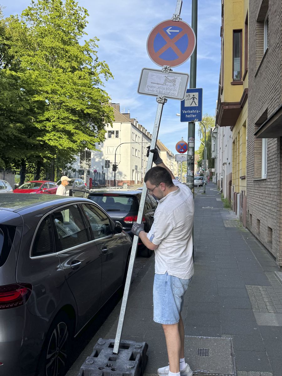 Baris Coskun stellt ein Halteverbotsschild mit Zusatzschild und Termin auf