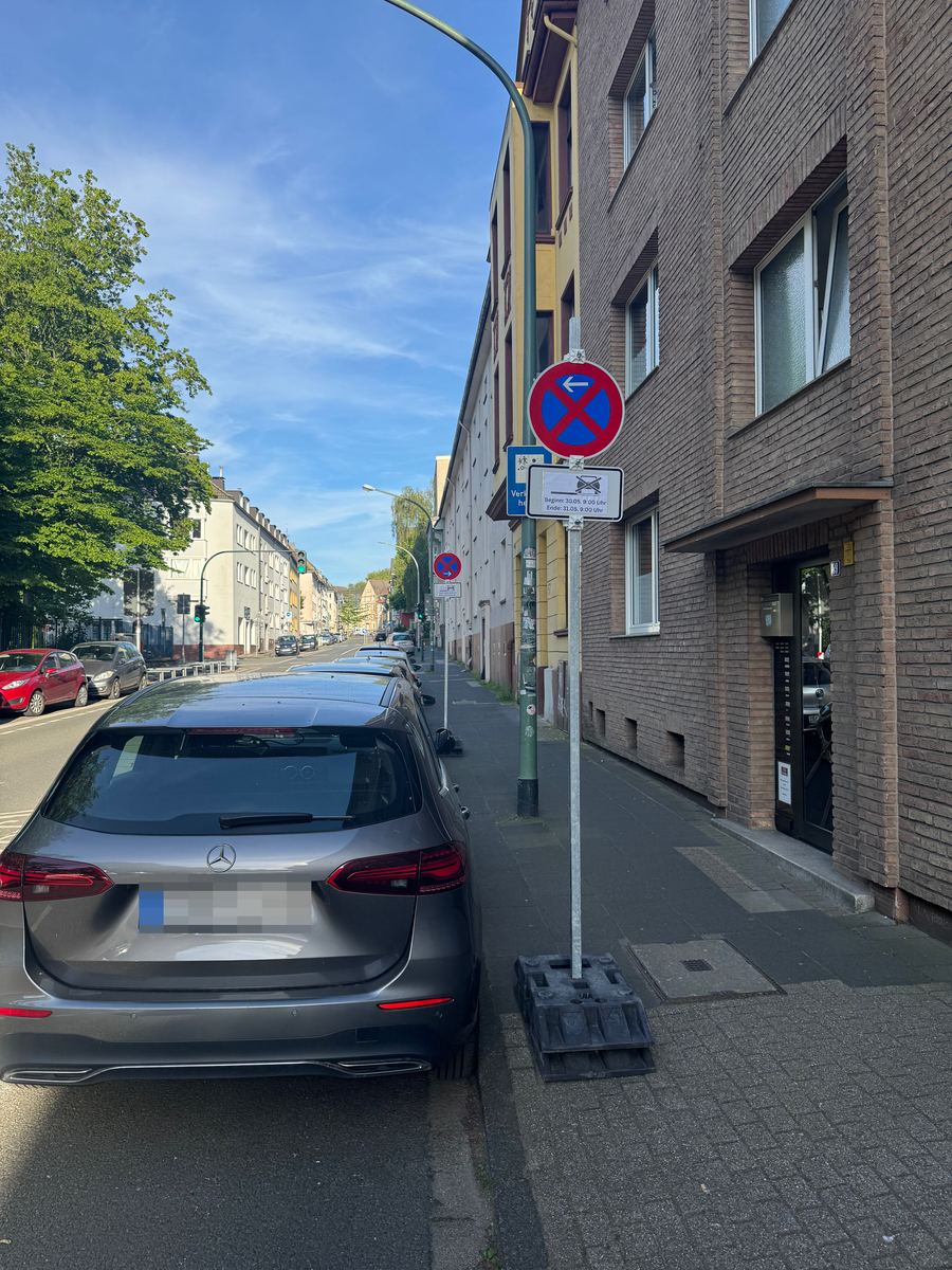 Halteverbotszone in einer Wohnstraße, Schild mit Beginn- und Endzeit